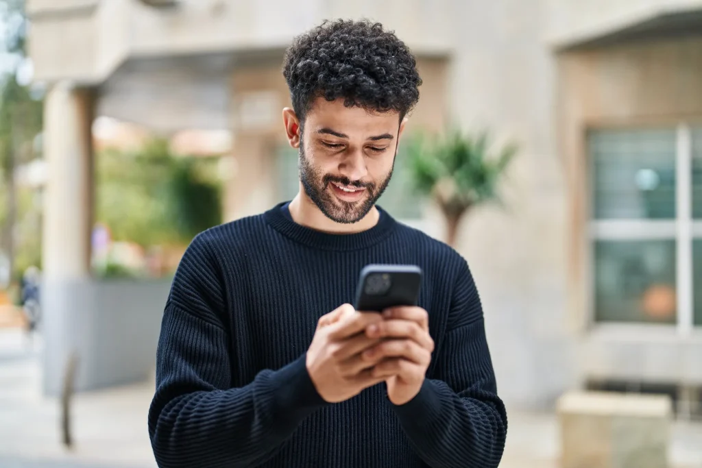 Man smiling while selecting a custom phone number on his smartphone using NY Mobile